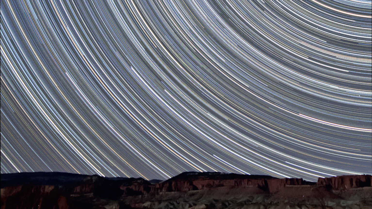 Kilka mil od parku narodowego Capitol Reef w Utah (USA). Te zdjęcia śladów gwiazd zostały wykonane w kierunku północnym. Gwiazdy wędrują nad oświetlonymi przez dopełniający się Księżyc czerwonymi skałami piaskowca. To sumaryczny obraz z 350 zdjęć, z których każde zostało wykonane z czasem naświetlania 90 sekund (łączny czas ekspozycji: 525 minut = 8,75 godziny). Zdjęcie wykonano obiektywem 10-20mm (@10mm f/4) i DSLR Canon 450D. U. Dittler